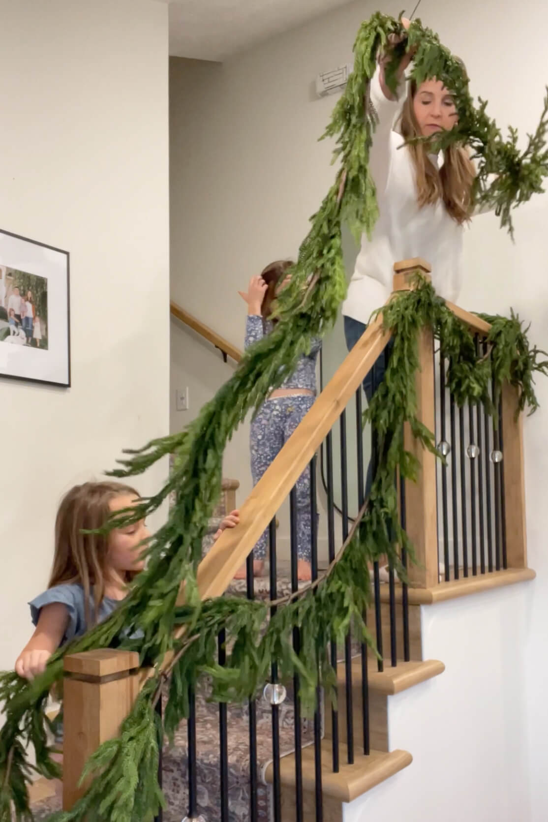 Adding a second layer of the best faux pine garland to a staircase.